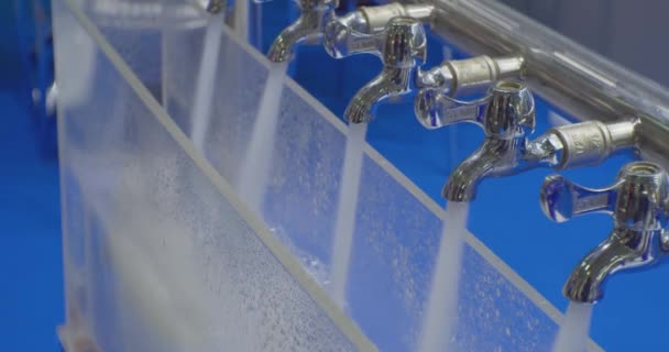 L'acqua pulita fuoriesce dai rubinetti metallici identici dei miscelatori.primo piano — Video Stock