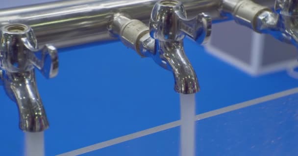 現代の技術です。水処理のための近代的な装置の実験と実証です。きれいな水のジェットは、いくつかの金属ミキサーのテープから注がれます。 — ストック動画