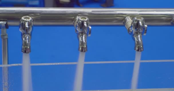 Chorros de agua limpia vierten de varios grifos de metal idénticos. primer plano — Vídeos de Stock