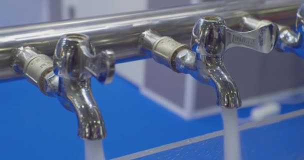Rent vatten rinner ut ur identiska metallkranar i blandarna.närbild — Stockvideo