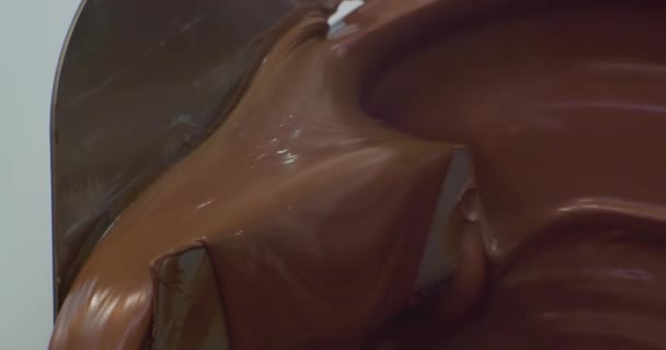 Industriële voedselproductie. Draaischijf van chocolademachine met hete gesmolten bruine chocolade. technologische procesclose-up — Stockvideo