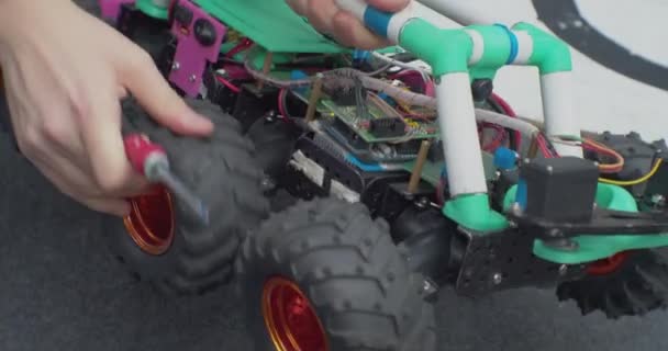 Repairing a homemade robot using a screwdriver. hands of a working man close up — Stock Video