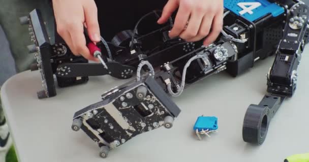 Menneskelige hænder er engageret i at reparere en brækket robot med en skruetrækker.close-up – Stock-video