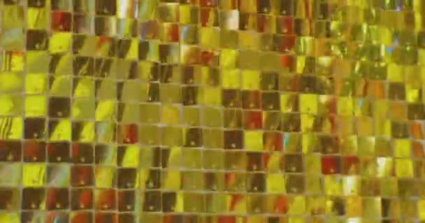Muchas placas de oro pequeñas y brillantes brillan, reflejando la luz del sol. fondo festivo abstracto — Vídeo de stock