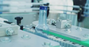 Modern endüstriyel üretim. Cam şişeler dolum hattı boyunca ilerler. Teknolojik işlemin yakın çekim görüntüleri.