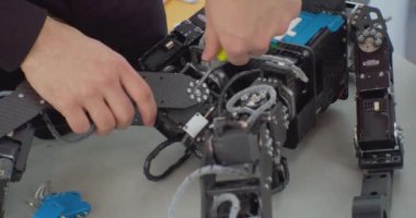 Bozuk robot tornavidayla birleştiriliyor. Çalışan bir adamın elleri. Yakından.