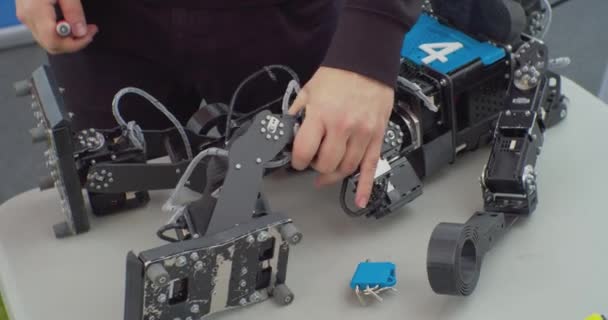 Mãos humanas estão envolvidas na montagem mecânica do robô usando uma chave de fenda. — Vídeo de Stock