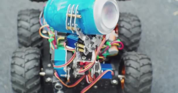 Un pequeño robot casero limpiador sobre ruedas mueve una lata de aluminio. primer plano — Vídeo de stock