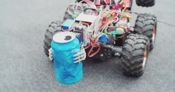 Un pequeño robot casero limpiador sobre ruedas mueve una lata de aluminio. primer plano — Vídeos de Stock
