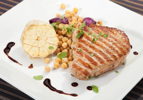 Grilled pork chop w peas and garlic — Stock Photo, Image