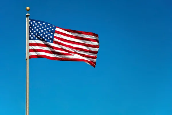 Ons Amerikaanse vlag zwaaien in de wind met mooie blauwe hemel in b — Stockfoto