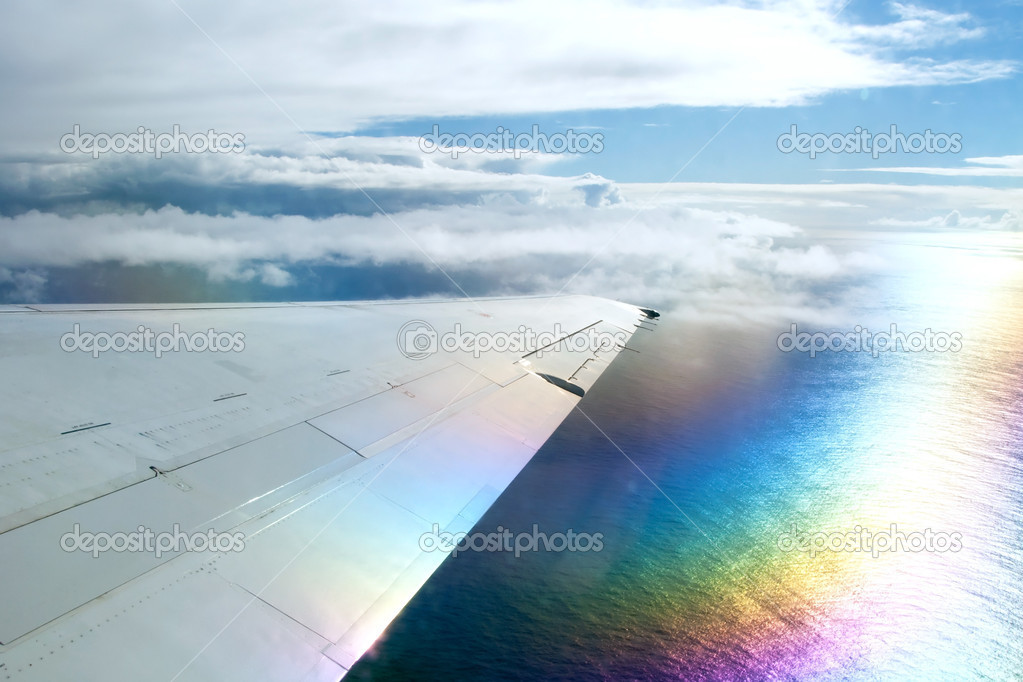 Wing of airplane flying above clouds in the sky and with a view 