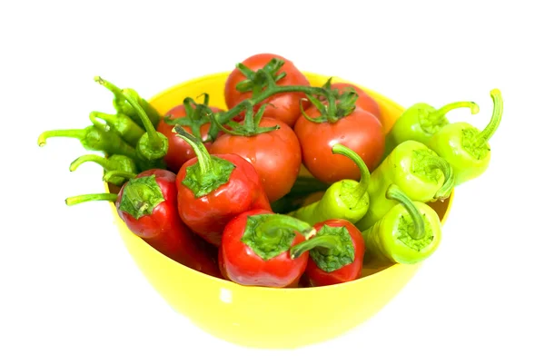 Varios pimientos frescos y tomates en tazón amarillo sobre fondo blanco — Foto de Stock