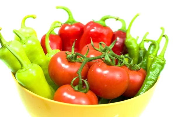 Varios pimientos frescos y tomates en tazón amarillo sobre fondo blanco — Foto de Stock