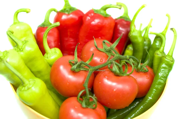 Varios pimientos frescos y tomates en tazón amarillo sobre fondo blanco — Foto de Stock