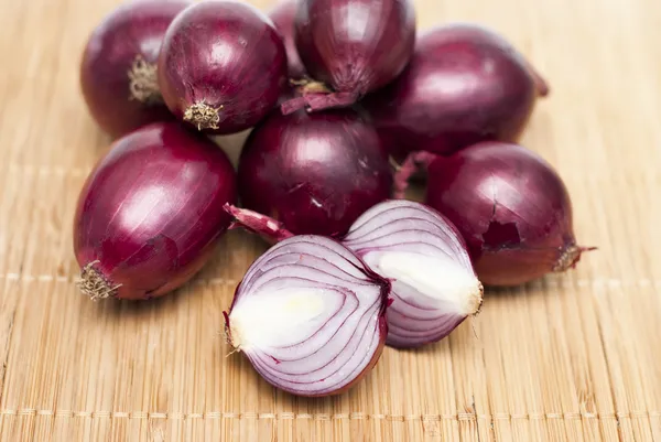 Cebollas bombilla roja sobre fondo de bambú —  Fotos de Stock