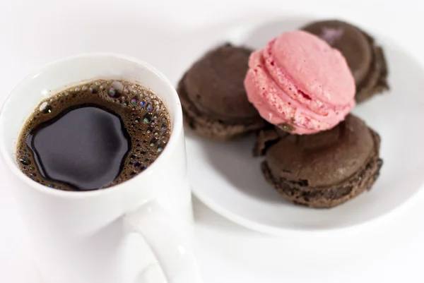 Taza de café con macarrones en tono marrón y rosa sobre fondo blanco — Foto de Stock