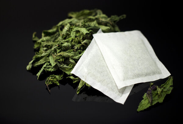 Мятные пакетики с мятными листьями на черном фоне
