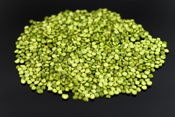 Green peas on a black background — Stock Photo, Image