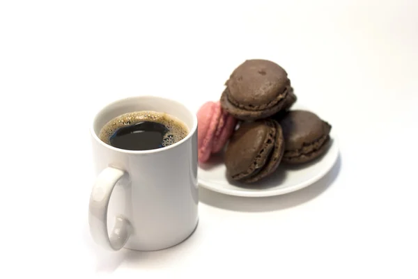 Taza de café con macarrones en tono marrón y rosa sobre fondo blanco — Foto de Stock
