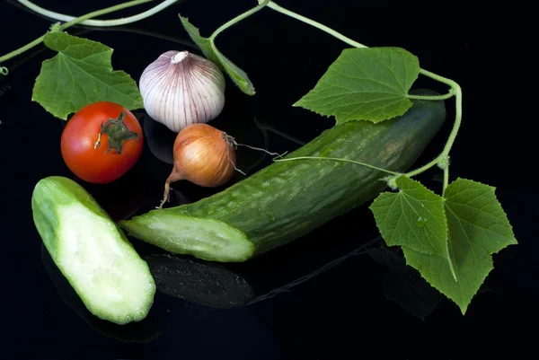 Onion garlic, tomato and cucumber on a black background — Stock Photo, Image