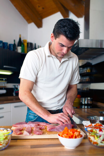 Молодой красивый мужчина готовит обед
