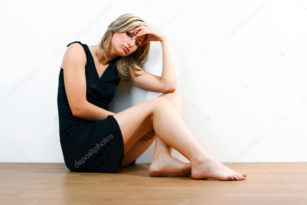 Young depressed woman sitting on floor