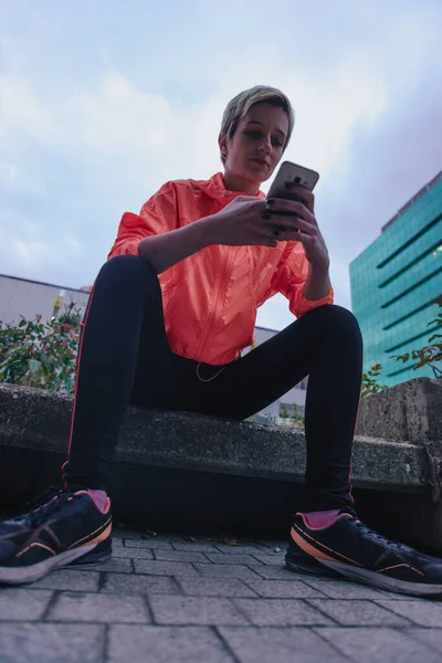 Sportif Güzel Sarışın Kız Telefonunu Kontrol Ederken Oturuyor Mola Veriyor — Stok fotoğraf