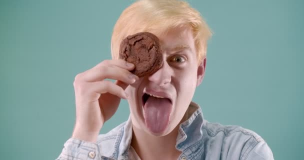 Loira Menino Está Fazendo Caras Com Biscoito Enquanto Come Brincando — Vídeo de Stock