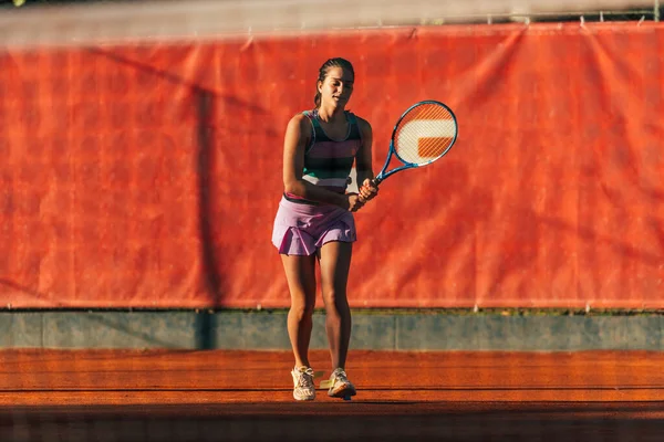 女子学生服姿の白人女性が粘土コートでテニスをする — ストック写真