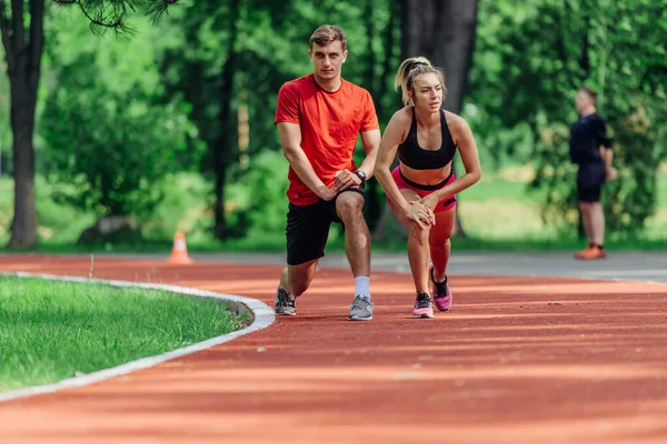 Pareja Joven Estirándose Antes Comenzar Rutina Jogging Matutino Una Pista — Foto de Stock