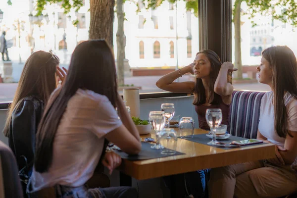 4人の素晴らしいと美しい女の子の友人が話していて カフェでぶらついている間に何かを話し合っている — ストック写真