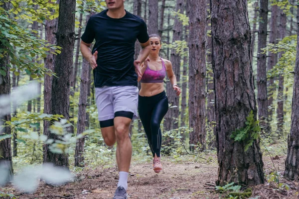 森の中をジョギングする男女の選手の写真を閉じます — ストック写真