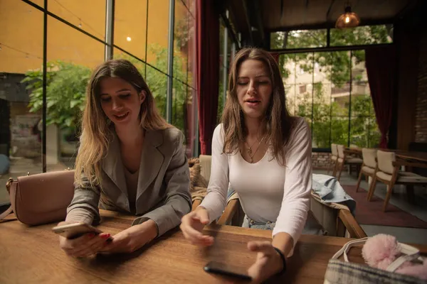 Две Привлекательные Красивые Сестры Проверяют Свои Телефоны Ресторане — стоковое фото