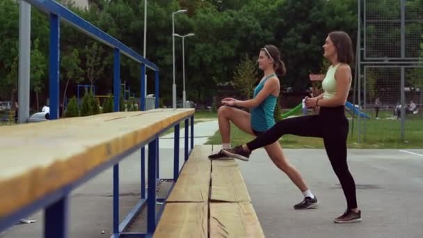 Две Привлекательные Красивые Девушки Растягивают Ноги Согреваясь Скамейке Замедленное Движение — Бесплатное стоковое видео