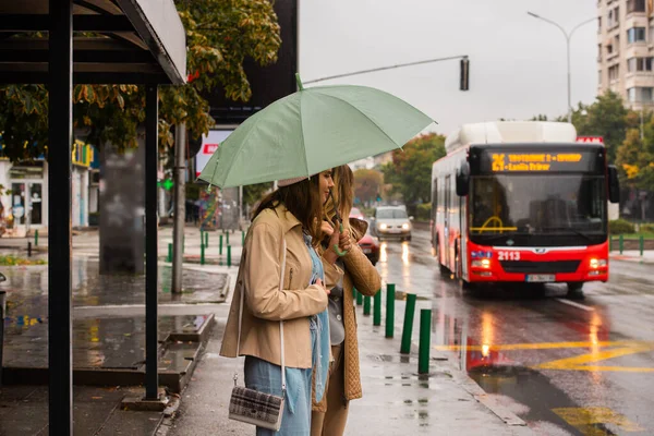 Autobus Přijíždí Autobusovou Zastávku Zatímco Něj Čekají Dvě Dívky — Stock fotografie
