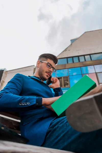 Empresário Elegante Usando Laptop Enquanto Sentado Banco Madeira Falando Telefone — Fotografia de Stock