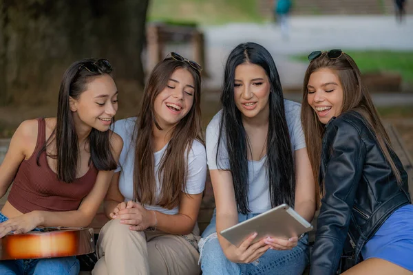 四个女孩一边笑一边看平板电脑上有趣的视频 — 图库照片