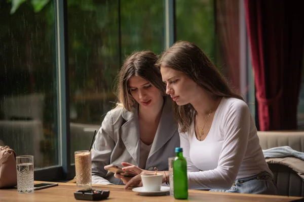 Dos Hermanas Están Mirando Teléfono Restaurante Mientras Llueve Afuera —  Fotos de Stock