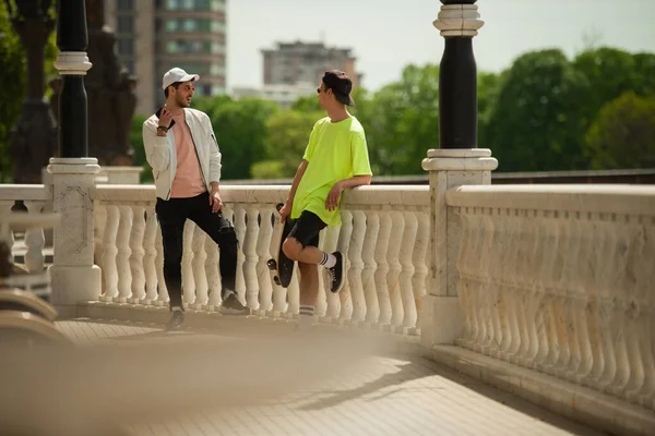 两个男性朋友靠在桥上聊天 — 图库照片