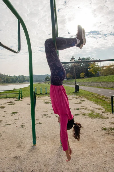 美しく魅力的なフィットの女の子は公園のトレーニングバーにかかっています — ストック写真