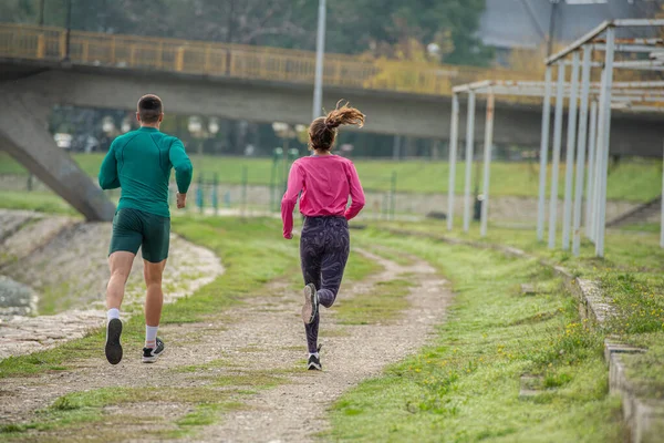 Attractive and strong friends are running together outside, in the morning