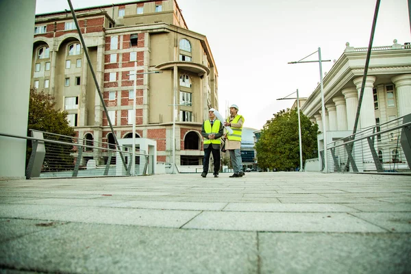 Zwei Leitende Bauarbeiter Stehen Und Sprechen Über Die Pläne Auf — Stockfoto