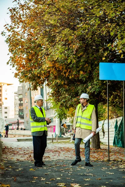 Zwei Bauarbeiter Laufen Zusammen Während Sie Sich Über Die Pläne — Stockfoto