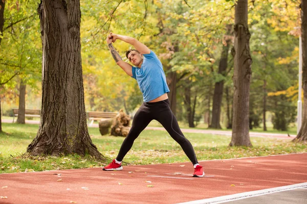 Attractive Handsome Strong Guy Stretching Warming Alone Park Red Track — Fotografia de Stock