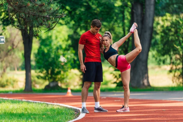 Mladý Sportovec Podporuje Svou Mladou Partnerku Zatímco Ona Protahuje Nohy — Stock fotografie