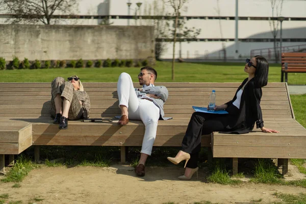 三个商人坐在长椅上谈论公司的事 — 图库照片