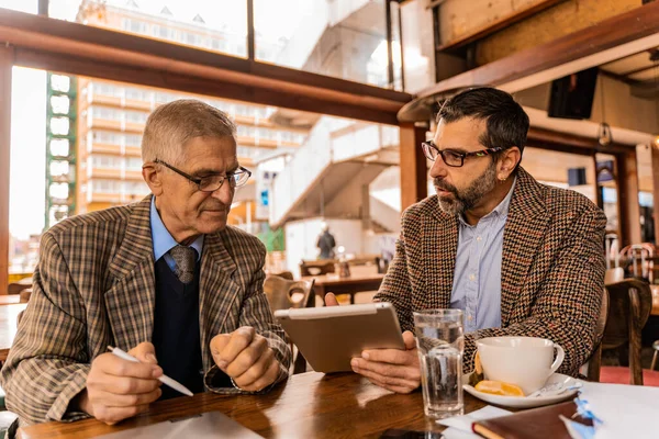 Δύο Ανώτεροι Επιχειρηματίες Συζητούν Έγγραφα Μαζί Ενώ Κάθονται — Φωτογραφία Αρχείου