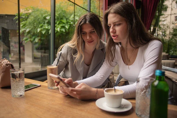 Dos Chicas Atractivas Sorprendentes Están Sentadas Mirando Teléfono Mientras Hablan —  Fotos de Stock