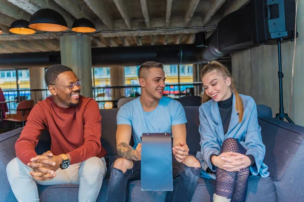 Tres Amigos Multirraciales Están Sentados Mirando Menú Juntos Mientras Sonríen —  Fotos de Stock
